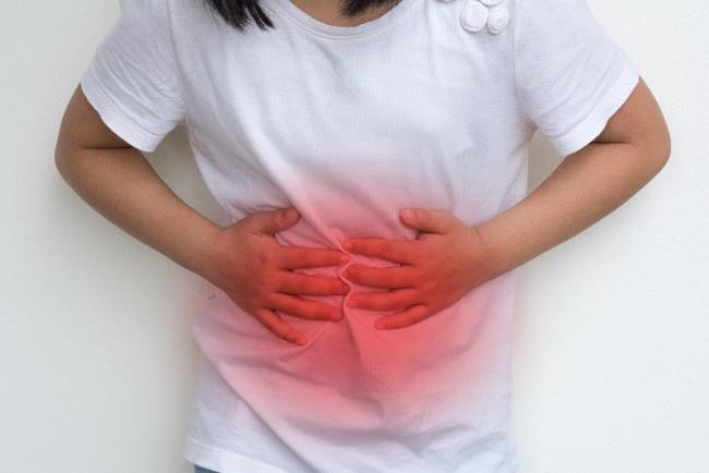אישה צעירה סובלת מכאבי בטן שיכולים להעיד על מחלת מעי דלקתית 